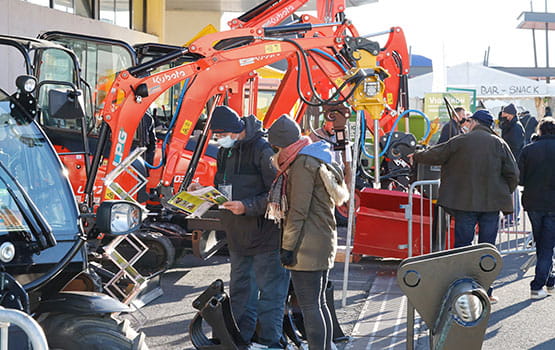 Visiteurs devant un tracteur rouge Kubota